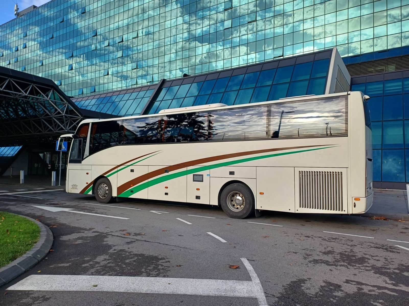 White coach in front of a glass building