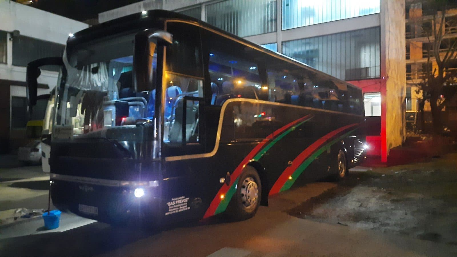 Black Van Hool coach at night, side view