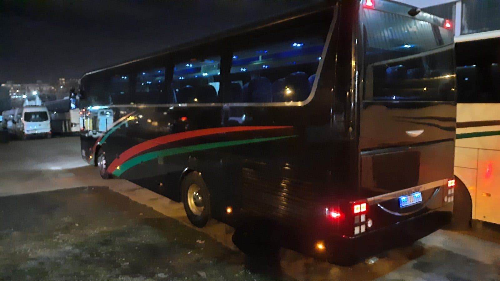 Black Van Hool coach at night, rear view
