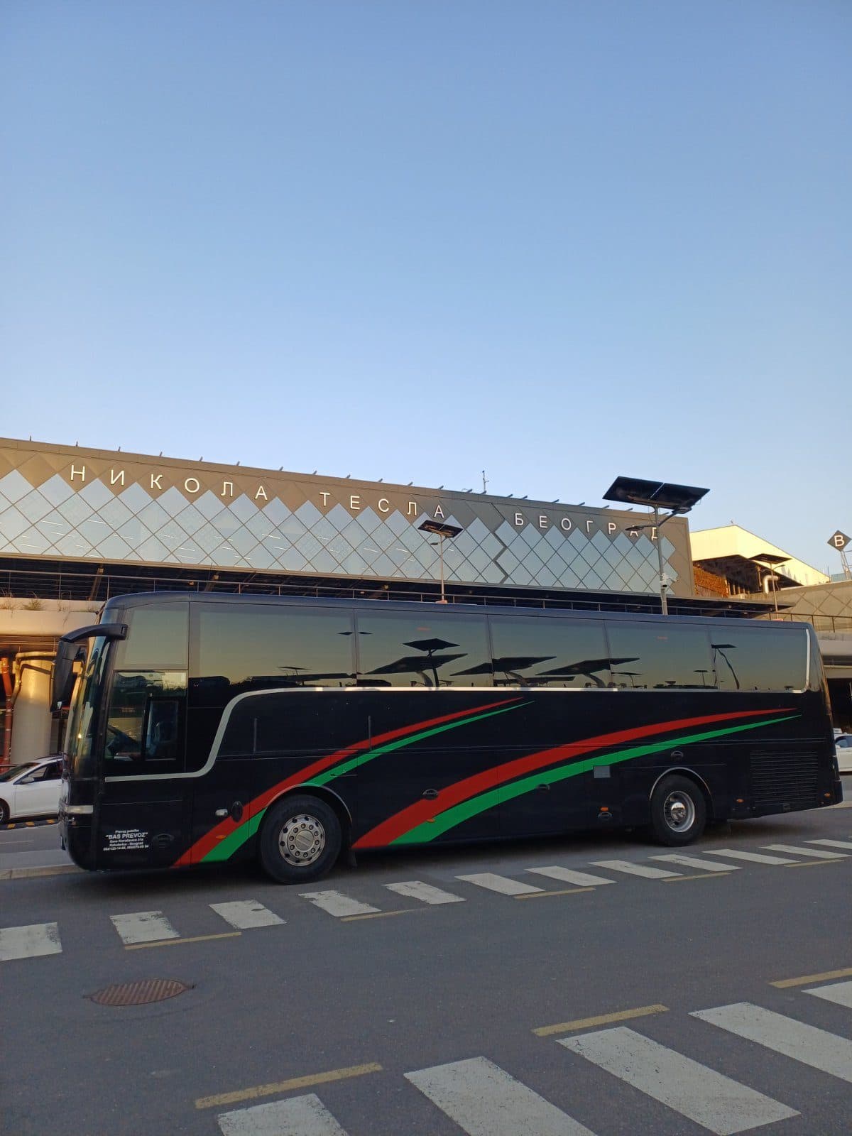 Black Van Hool coach in front of the Nikola Tesla Airport terminal