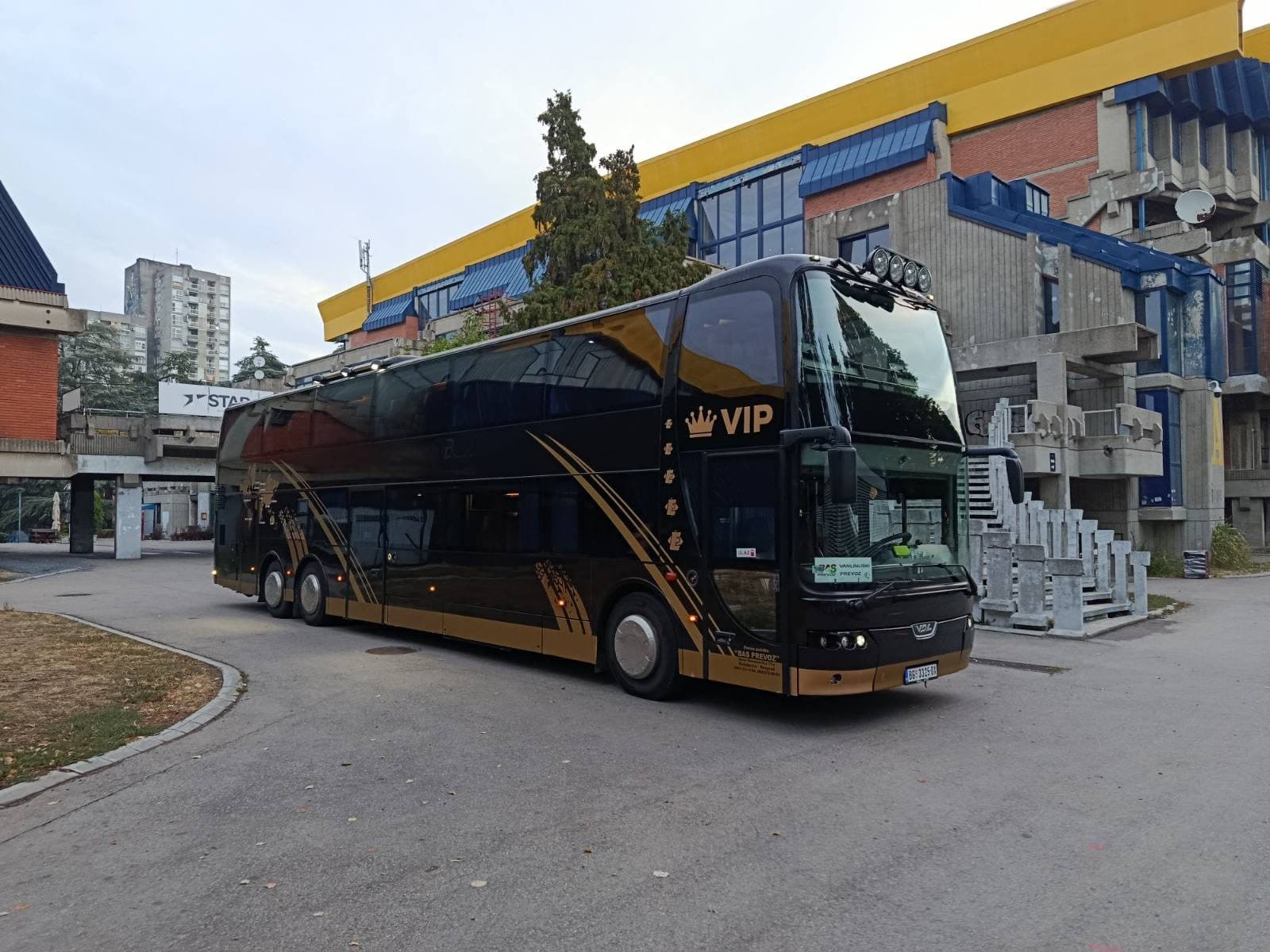 Black and gold BAS PREVOZ VDL Synergy VIP coach in front of a sports hall