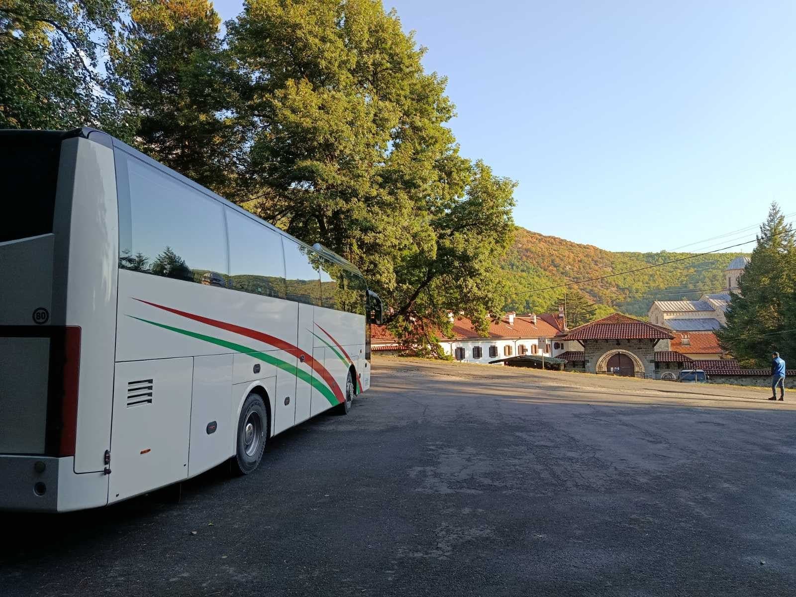White coach in front of a monastery lodge in morning sun