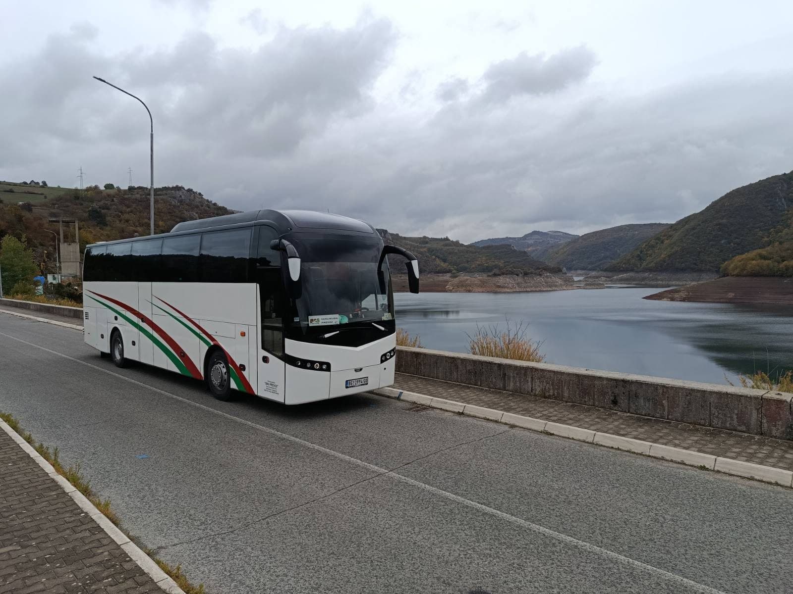 White BAS PREVOZ coach on the road beside Lake Uvac